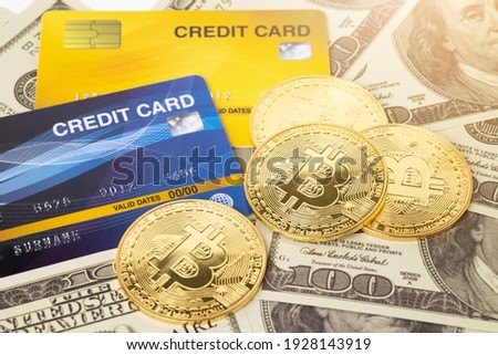 Bitcoin cryptocurrency on hundred us dollars with credit card. Close up electronic golden coin. Business and financial concept.