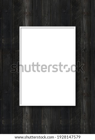 White picture frame hanging on a black wooden wall. Blank mockup template