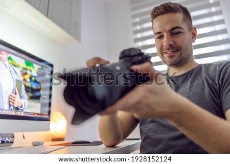 Junior graphic designer and photographer checking out a raw material on the professional camera. Work from indoor home office, freelancer job