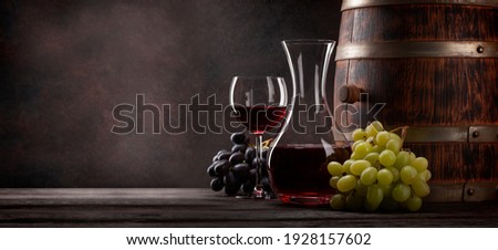 Wine decanter, glass of red wine and old wooden barrel. With copy space