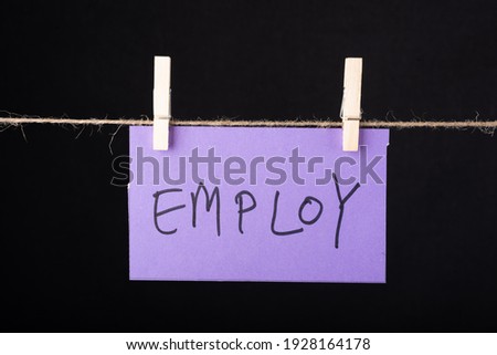 Employ word written on a Purple color sticky note hanging with a wire on black background