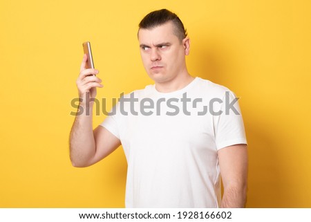 Angry man holding a smartphone. Aggressive man talking on the phone. 