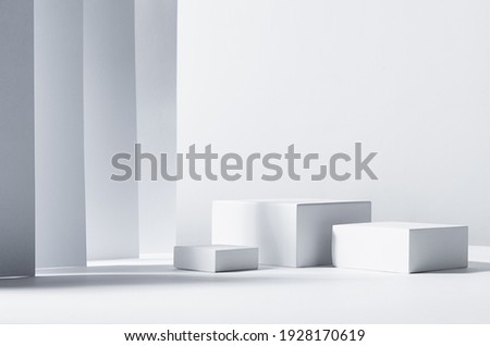 Minimalist abstract design for presentation and product display - white square podiums in sunlight with shadow in white geometric interior.