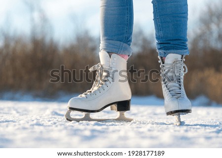 Close-up of legs ins ice-skates while standing on a frozen lake in winter