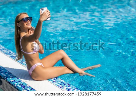 Woman taking a selfie on the pool edge on a sunny day