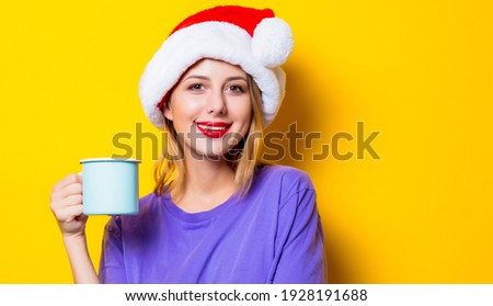 Young style girl in purple clothes and Christmas hat and cup on yellow background.  Clothes in 1980s style