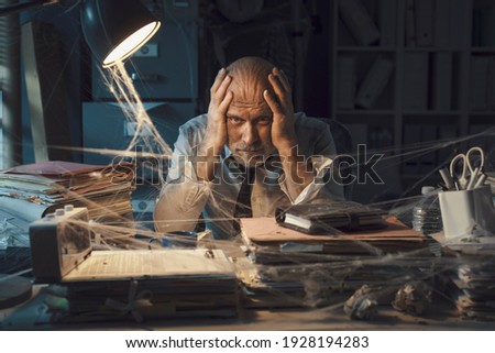 Desperate businessman sitting at desk in his abandoned office: business failure and financial crisis concept Royalty-Free Stock Photo #1928194283