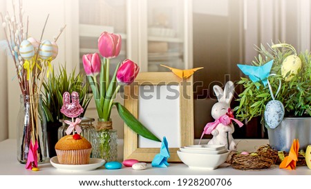 Easter creative home decoration from a bouquet with decorative eggs, Easter paper bunny, pussy willow branches, photo frames, Easter  accessories on the table