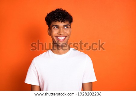 Photo of positive dark skin guy beaming smile look empty space thinking isolated on orange color background