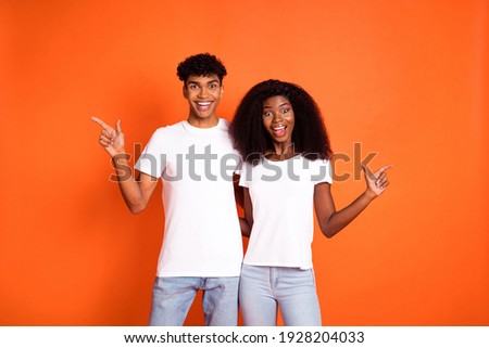 Photo of young smiling amazed afro couple hug each other pointing fingers copyspace isolated on orange color background
