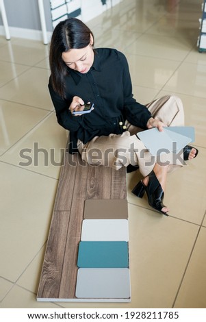 Interior designer choosing materials for home renovation. Woman laying out samples on the floor and matching the color of the walls to the parquet board. House decoration, small business concept