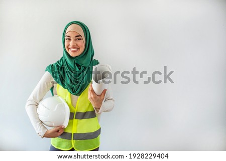 Female architect and engineer in hidjab and hardhat. Muslim architect woman. Engineer Woman hold Blue Print architects at Construction site or Building site of highrise Building.working woman concept