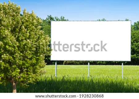 Blank advertising billboard immersed in a rural scene with blurred tree in the foreground - concept image with copy space.