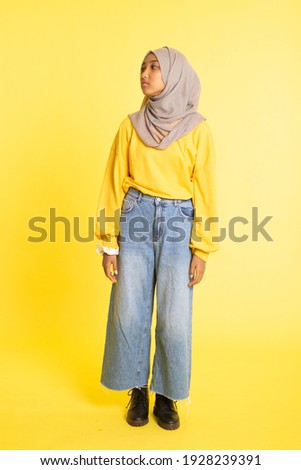 Fashion portrait of young beautiful asian muslim woman with wearing hijab isolated on yellow background.