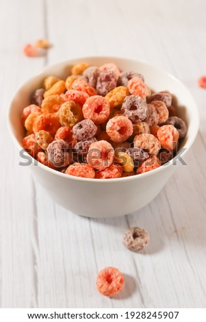 A bowl of Colourful cereal on white wooden table. Its crunchy and sweet for breakfast. Favorit kids 