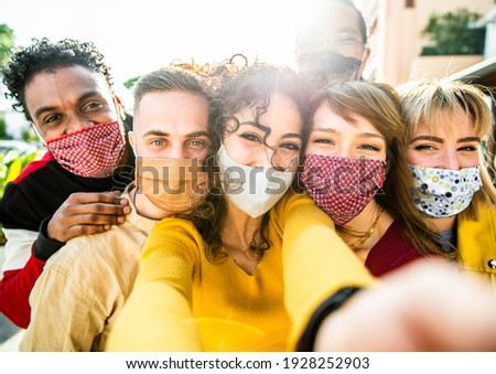 Happy friends wearing face masks taking a selfie outdoor - New normal friendship concept with young people having fun in the city - Main focus on central girl Royalty-Free Stock Photo #1928252903