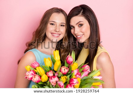 Photo of optimistic nice long hairdo ladies hold flowers wear pastel dress isolated on pink color background