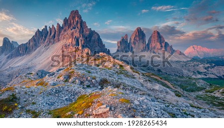 Unbelievable summer sunrise with Paternkofel and Tre Cime Di Lavaredo mpountain peaks on background. Majestic morning scene of Dolomite Alps, Italy, Europe. Traveling concept background Royalty-Free Stock Photo #1928265434
