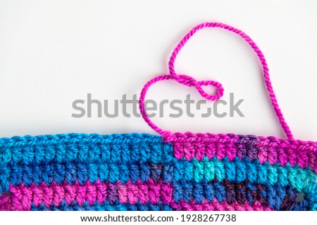 Crochet product from multicolored threads.
A heart made of pink thread is laid out on a white background
Handmade backdrop. Very peri 