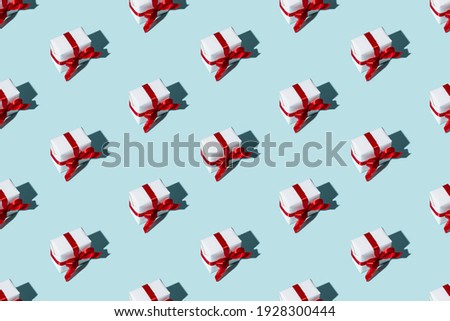 Blue holiday background. Seamless pattern. Gifts decor. Festive composition. Minimalist diagonal arrangement of white boxes with red ribbon bows isolated on light.