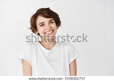 Portrait of authentic happy woman without makeup, smiling at camera, standing cute against white background. Royalty-Free Stock Photo #1928302757