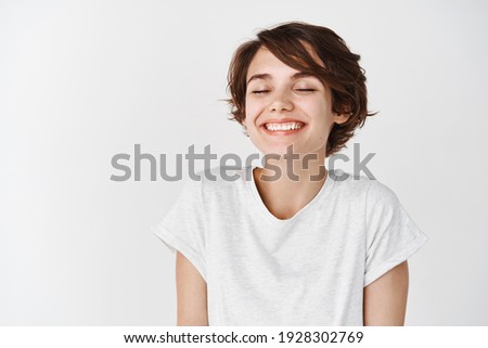 Beautiful caucasian woman dreamy smiling with eyes closed, standing relaxed and happy against white background. Copy space