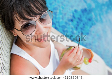 Close-up portrait young pretty woman drinking coconut cocktail against outdoor pool. Top view . Concept photo recreation and tourism