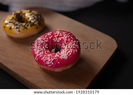 Donuts on a wooden stand on a black background. 