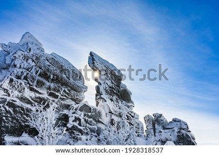 high stone cliff covered with snow in frosty sunny winter
