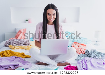 Photo of cute pretty young lady sleepwear sitting bed pile clothes communicating modern device indoors room home