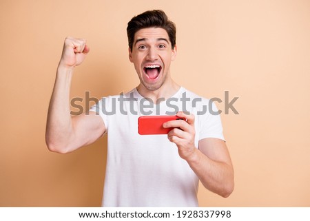 Portrait of astonished handsome guy fist up open mouth shout yeah isolated on beige color background
