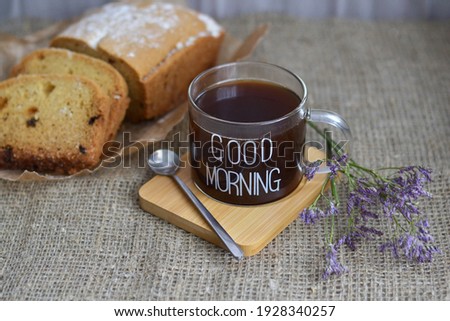 Cup of coffee on wooden board with text good morning with tasty homemade cake on flaxen canvas napkin. 