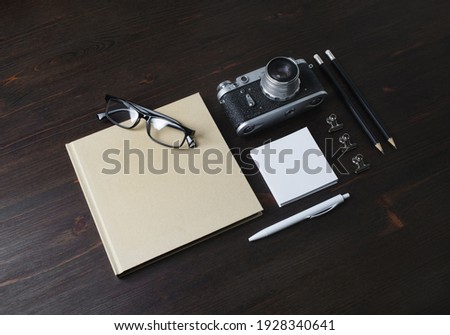 Blank stationery and vintage camera on wood table background.