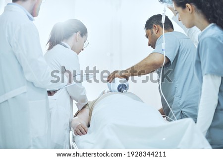 Team of doctors in uniform saving the life of patient in reanimation room at hospital Royalty-Free Stock Photo #1928344211