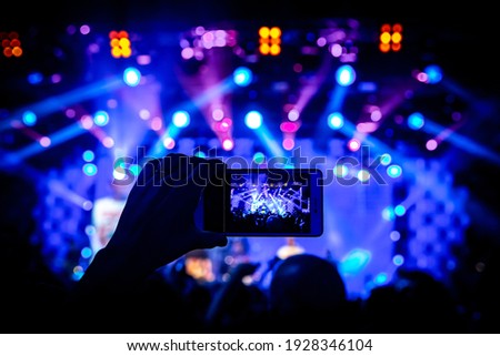 Man takes a picture of the show at the concert hall using a smartphone