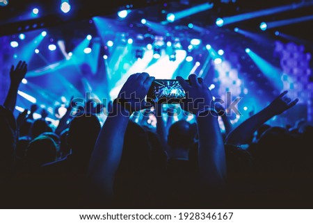 Man takes a picture of the show at the concert hall using a smartphone
