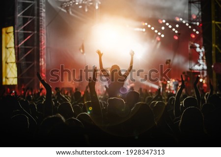 Raised hands in honor of a musical show on stage, People in the hall Royalty-Free Stock Photo #1928347313