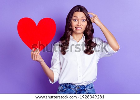 Photo of grimacing lady hold paper heart finger head look camera wear white shirt isolated violet color background