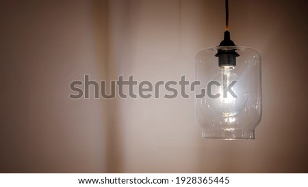 Light bulb on empty beige wall with copy space for inspiration or idea under light bulb. Royalty-Free Stock Photo #1928365445