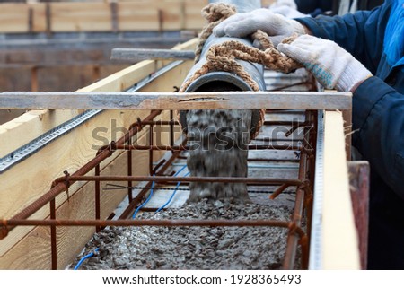 automatic concrete feed using a concrete pump for filling reinforced beams, close-up with a blurred background, builder fills with the concrete reinforcement frame, construction of a private house Royalty-Free Stock Photo #1928365493