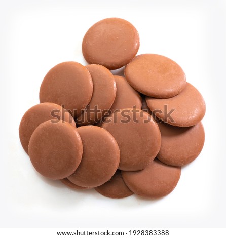 Lots of milk chocolate disks on white background. Isolated. View from above