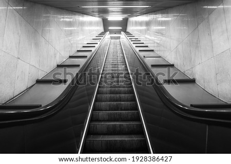 Perspective of mobile staircase in Milan's underground station. Light at the end of the tunnel. Monochromatic. Royalty-Free Stock Photo #1928386427