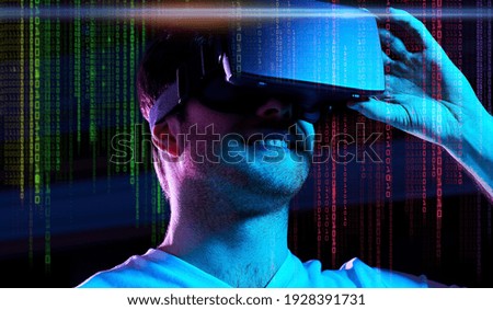 3d technology, virtual reality, entertainment and people concept - young man in vr glasses playing game over ultra violet neon lights and binary code on dark background