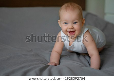 Cute Baby Smiling on the gray bed stock photo. First teeth. Image with selective focus