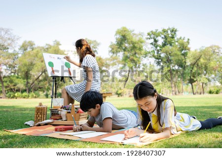 A group of diversity elementary school children enjoyed Paint a painting in the park. They do outdoor activities together. Friendship and Learning outside the classroom concept Royalty-Free Stock Photo #1928407307