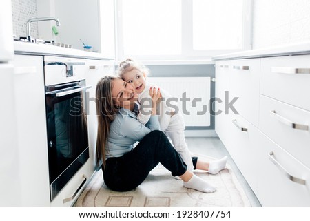 Happy caucasian mother with little daughter playing at the kitchen. happy mother and little child girl hugging having fun playing enjoy funny moments good time together.