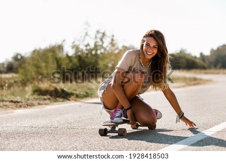 Sporty woman riding on the skateboard on the road. Longboarding, female.