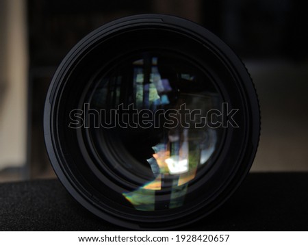 Camera lens with lens reflections.  Dark background.  Colored highlights and reflections.  Macro.  Glass and reflection.