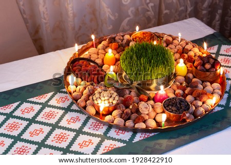 Novruz traditional tray with green wheat grass semeni or sabzi, sweets and dry fruits and festive candles with tea. Traditional celebration of spring equinox in March in Azerbaijan 