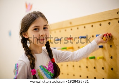 the girl plays with wooden pegboard with round pegs Royalty-Free Stock Photo #1928428781
